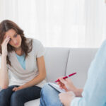 Worried woman sitting while therapist looking at her